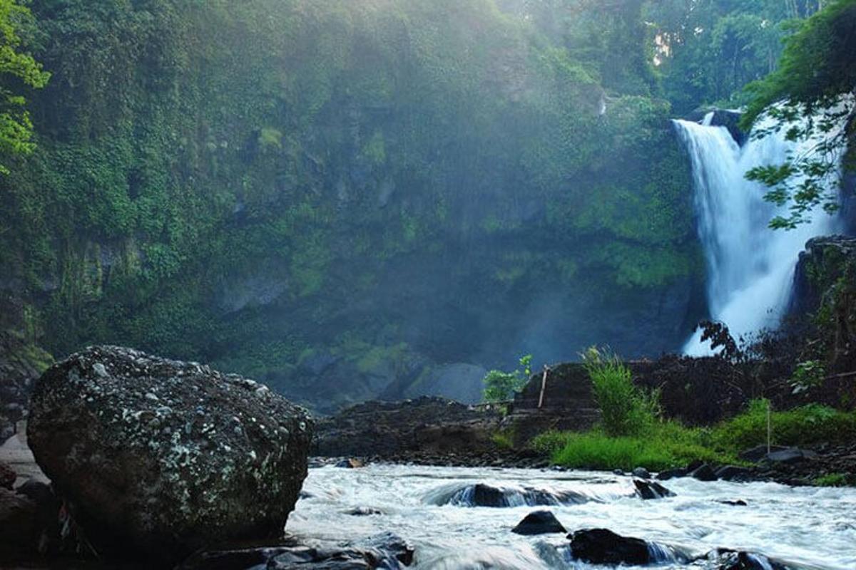 a waterfall in the middle of a river with a rock