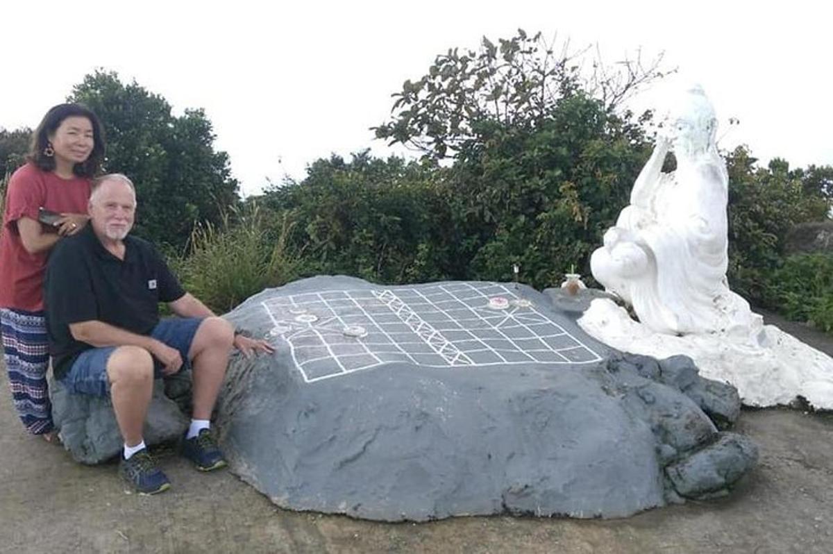 um homem e uma mulher sentados em uma rocha ao lado de uma estátua