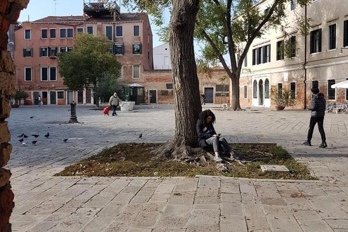 a woman sitting next to a tree in a courtyard