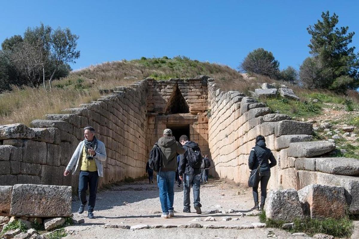 μια ομάδα ανθρώπων που περπατούν μπροστά από ένα πέτρινο κτίριο