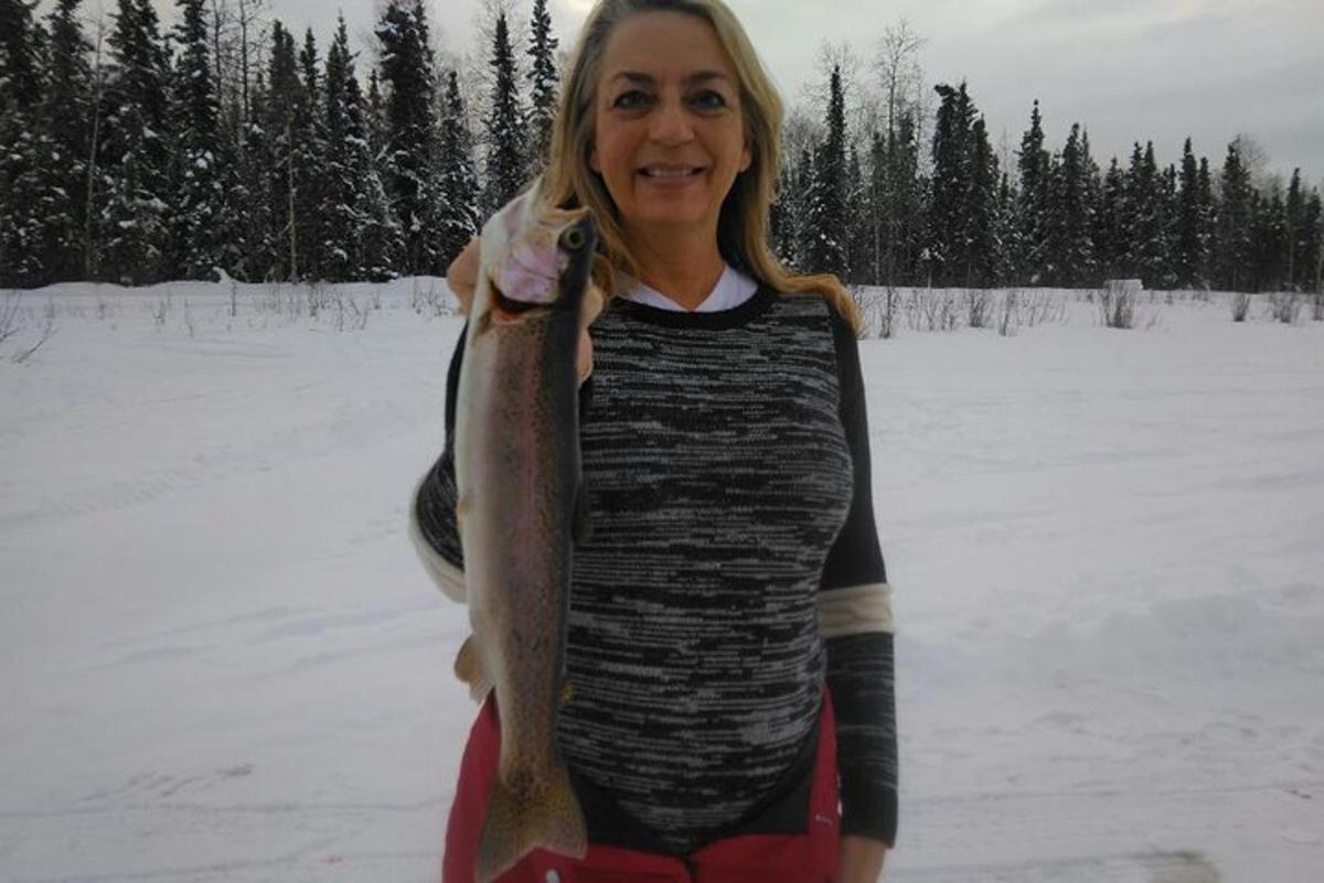 a woman holding a fish in her hand in the snow