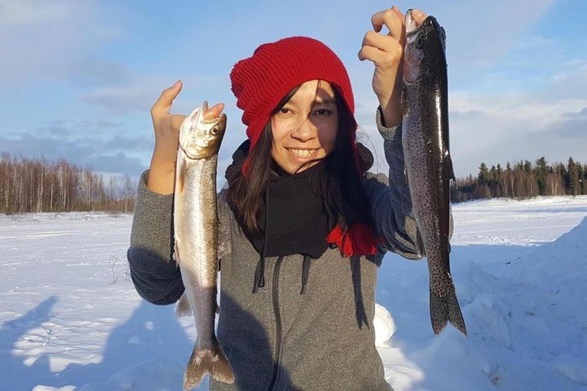 a woman holding two fish in the snow