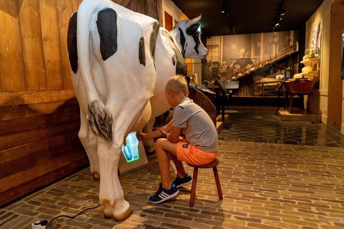 un uomo seduto su uno sgabello accanto a una mucca finta