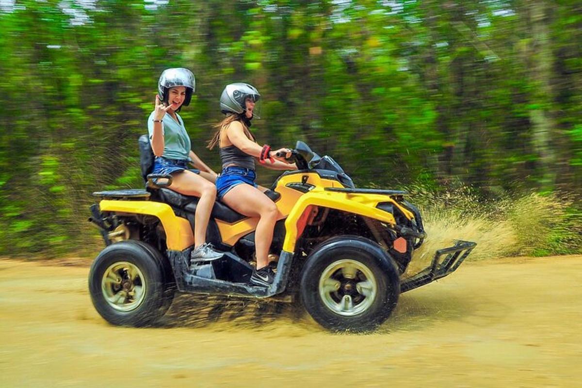 duas pessoas andando em um quadriciclo em uma estrada de terra