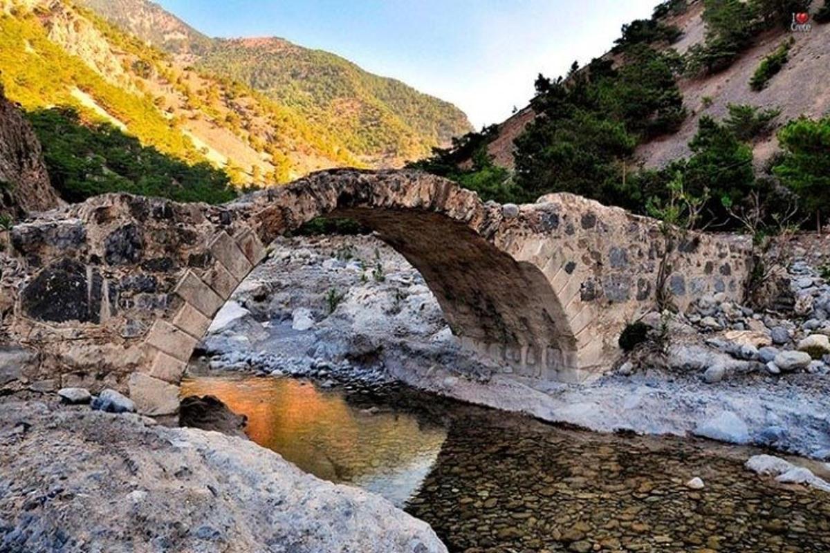 a stone bridge over a river in a mountain
