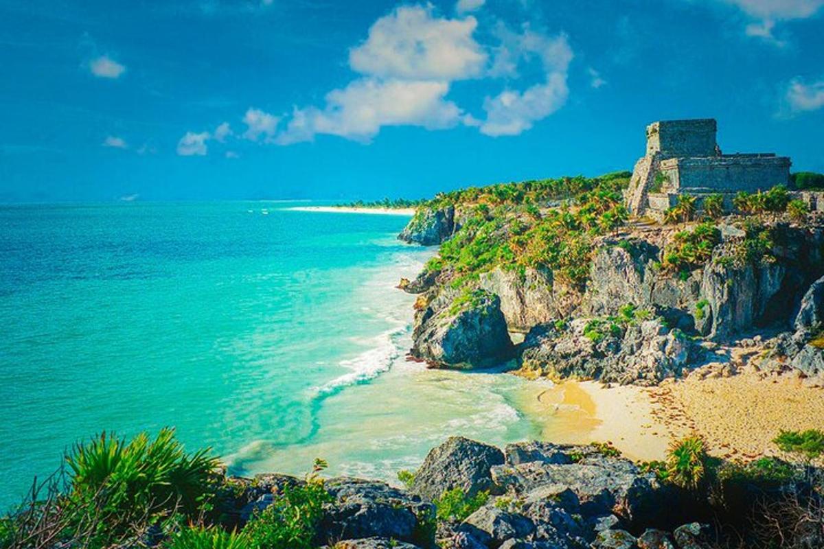 a beach with a building on a cliff next to the ocean