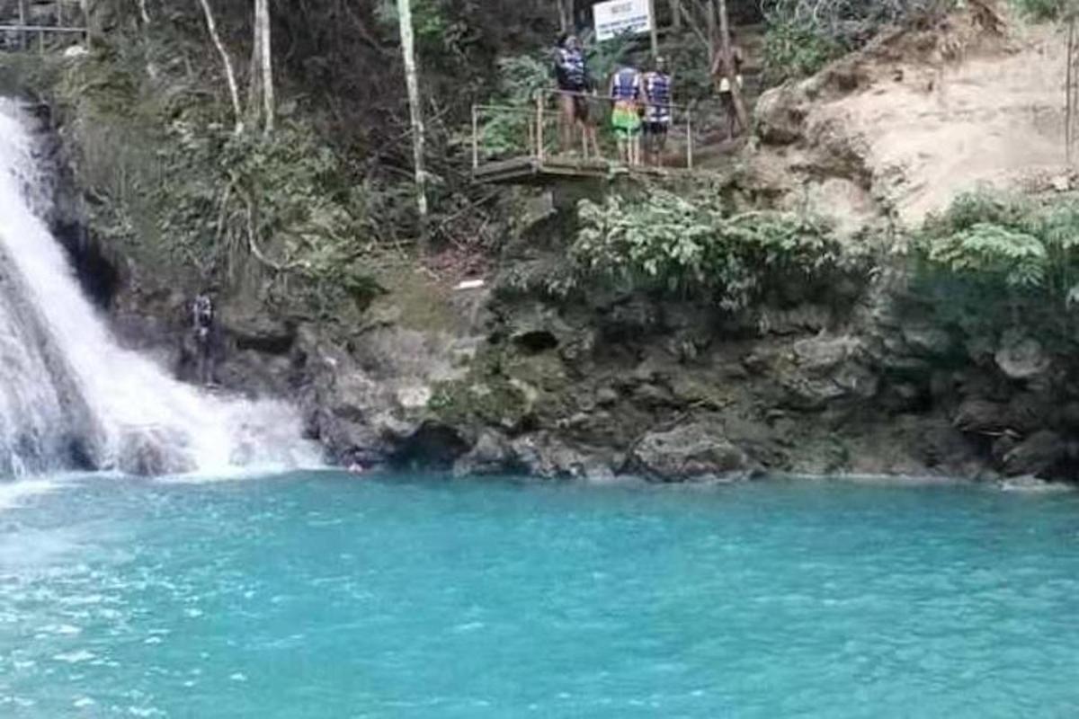 un bassal d'aigua blava al costat d'una cascada