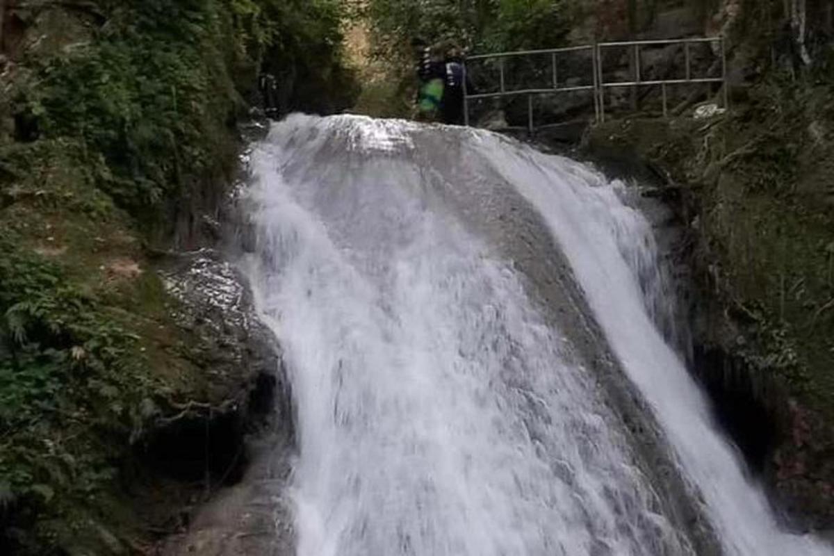 una cascada al vessant d'una muntanya amb gent dempeus a sobre