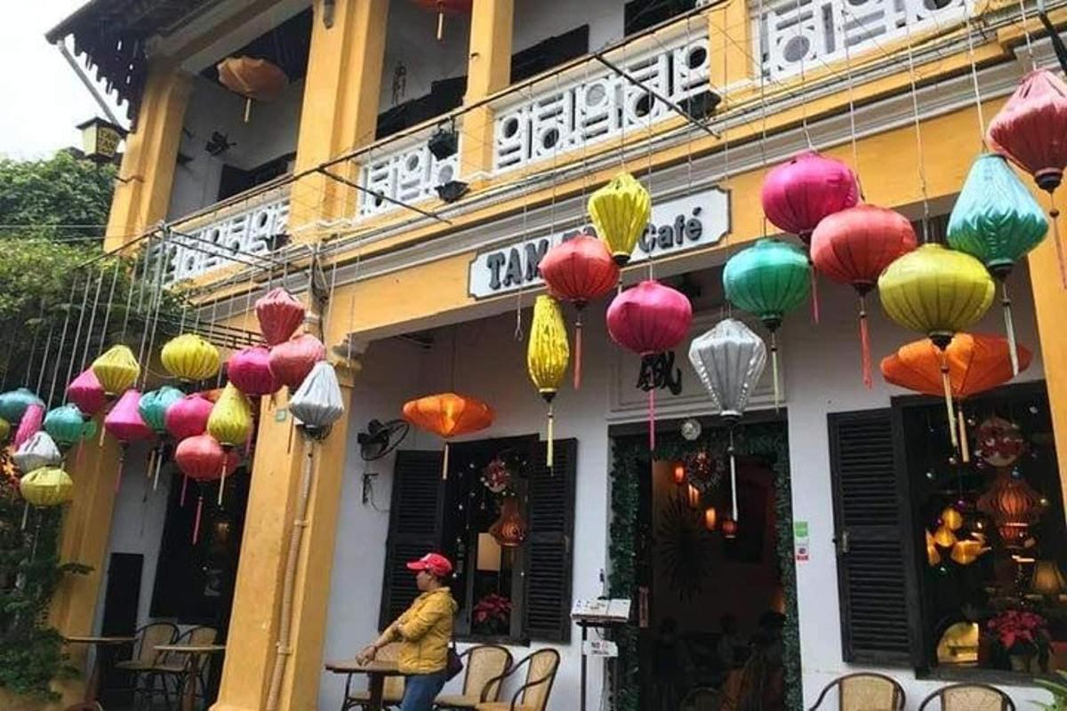 Una mujer parada afuera de un edificio con linternas de colores.