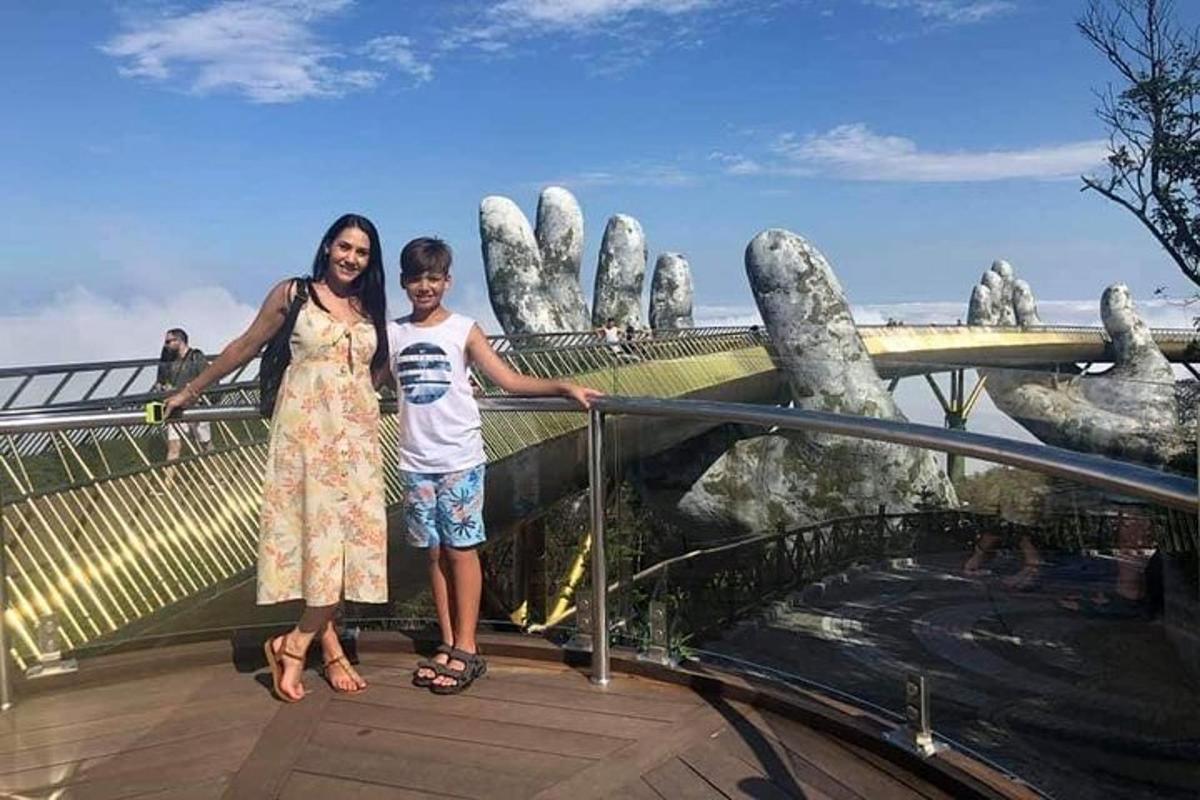 seorang wanita dan seorang budak lelaki berdiri di atas laluan pejalan kaki di hadapan tangan