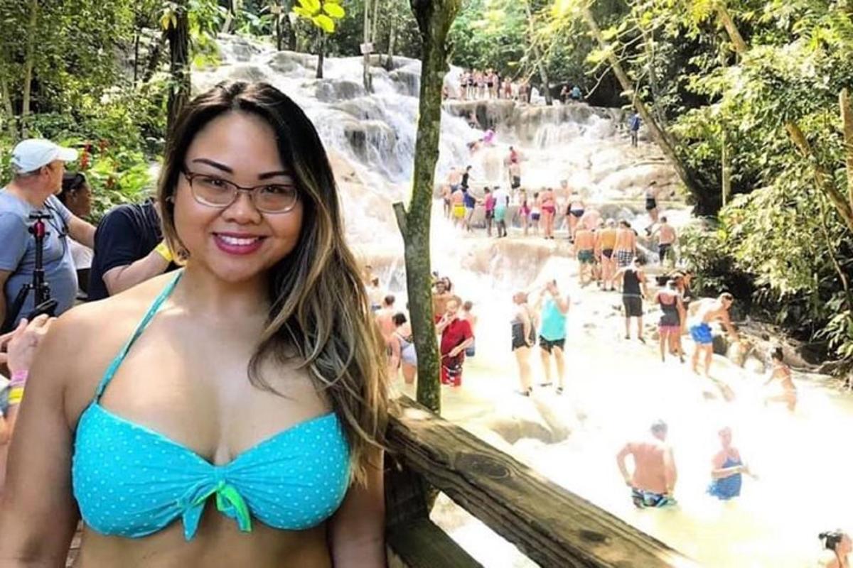 Una mujer en bikini azul parada frente a una cascada.