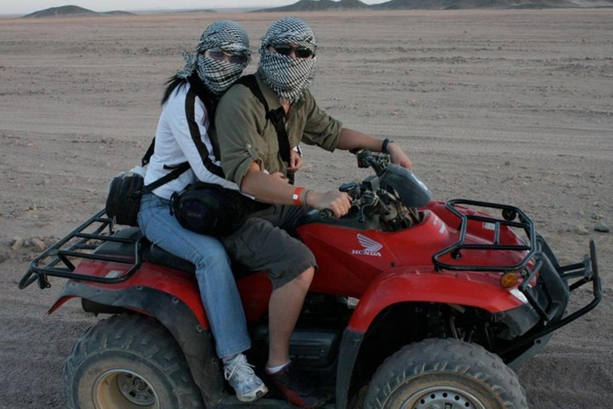 çölde bir atv'de oturan iki kişi