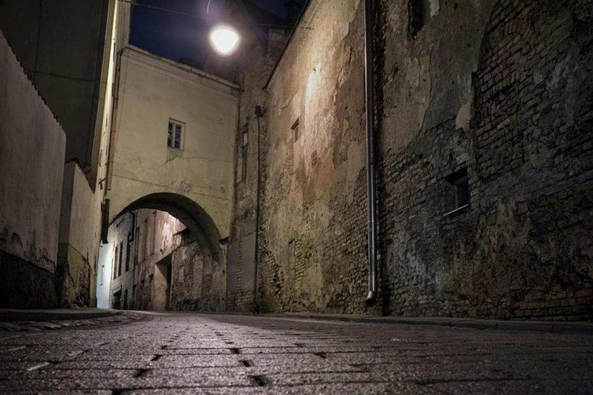 an alley with an archway in an old building at night