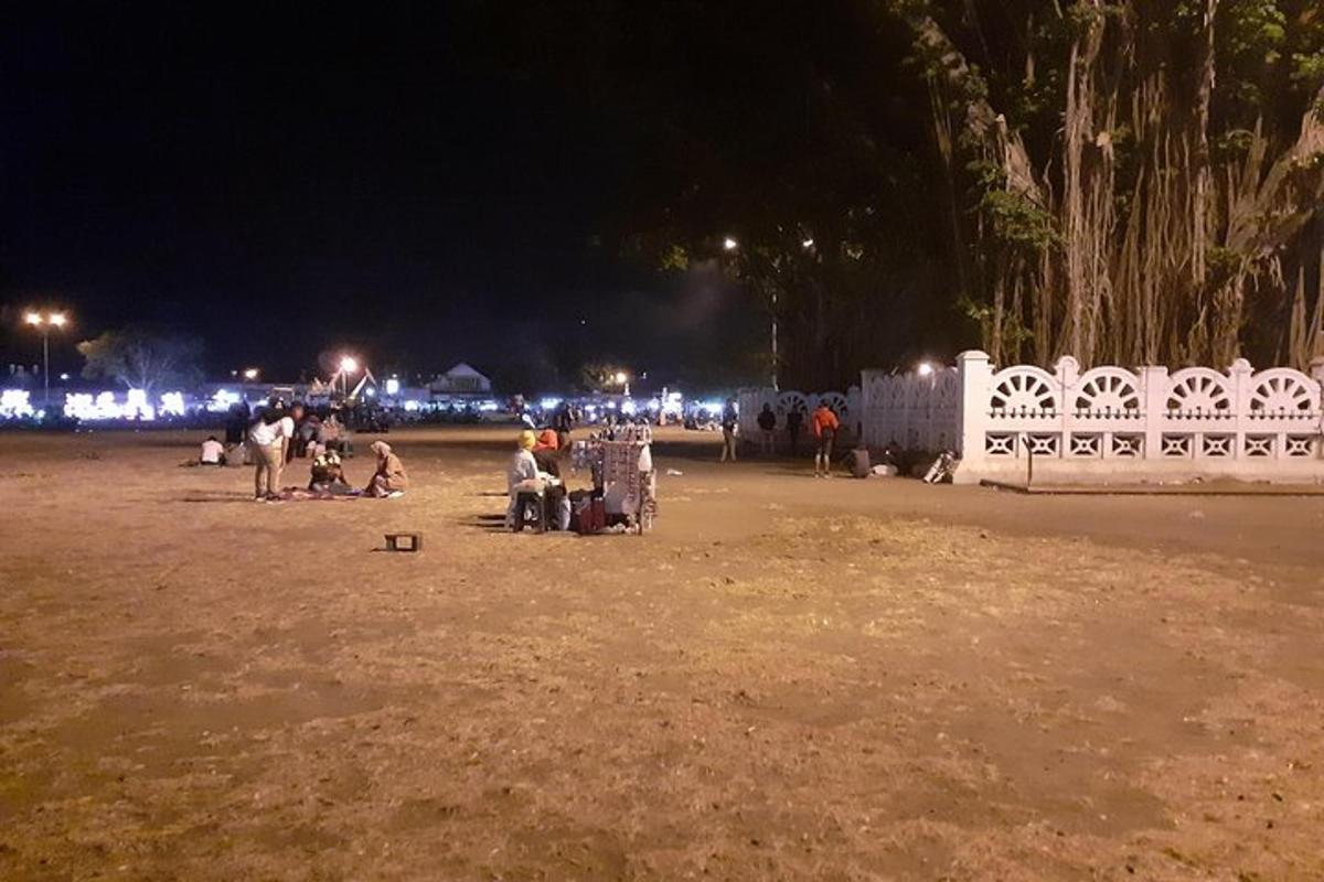 um grupo de pessoas sentadas em um campo à noite