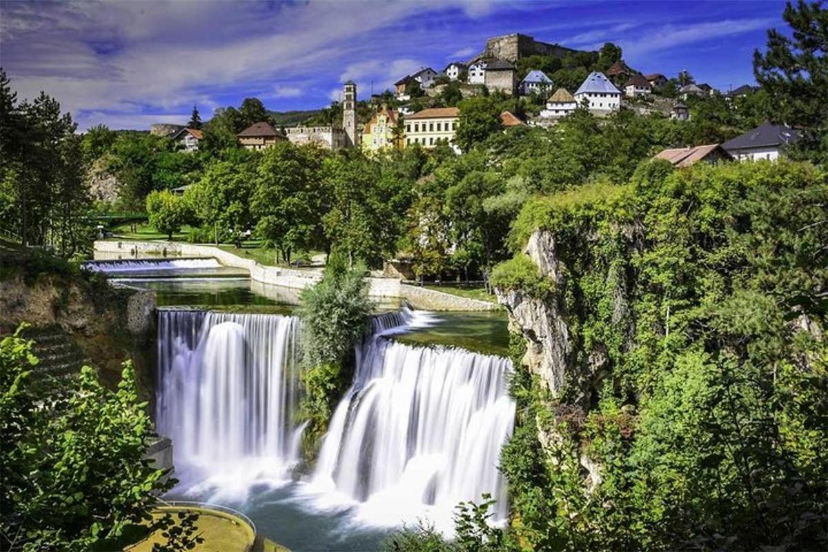 a waterfall in a river with houses in the background
