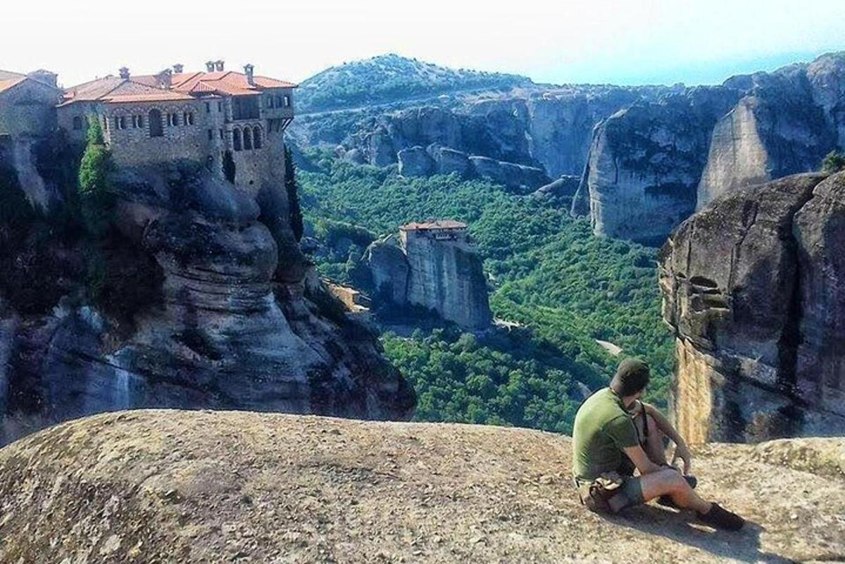 a man sitting on the edge of a cliff looking at the canyon