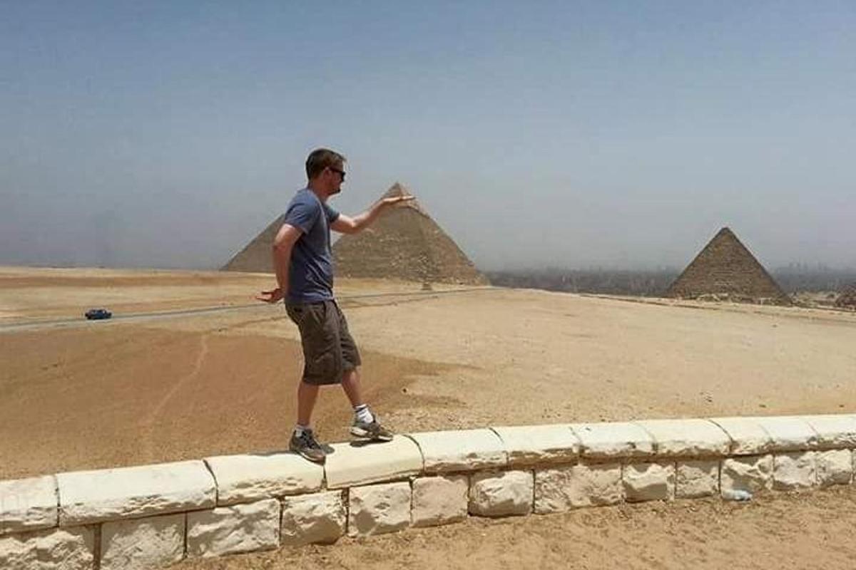 mies seisoo pyramideilla koristetulla muurilla