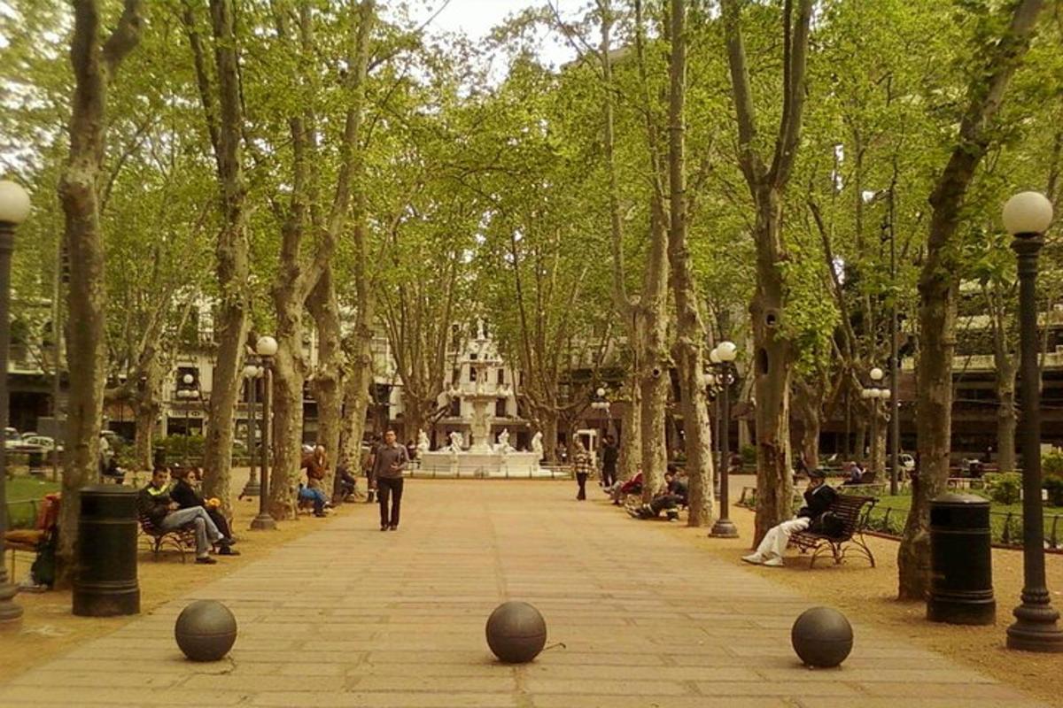 ένα πάρκο με ένα σιντριβάνι και ανθρώπους που κάθονται σε παγκάκια