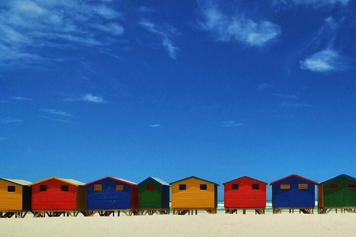 un rând de cabane de plajă colorate pe plajă