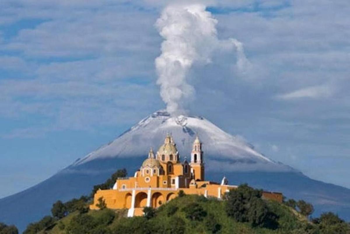 um edifício em uma colina com um vulcão ao fundo