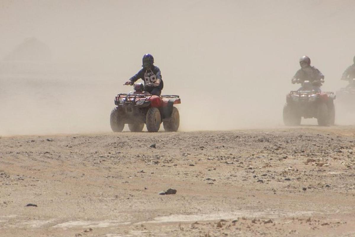 kolm inimest sõidavad ATV-dega mullaväljal