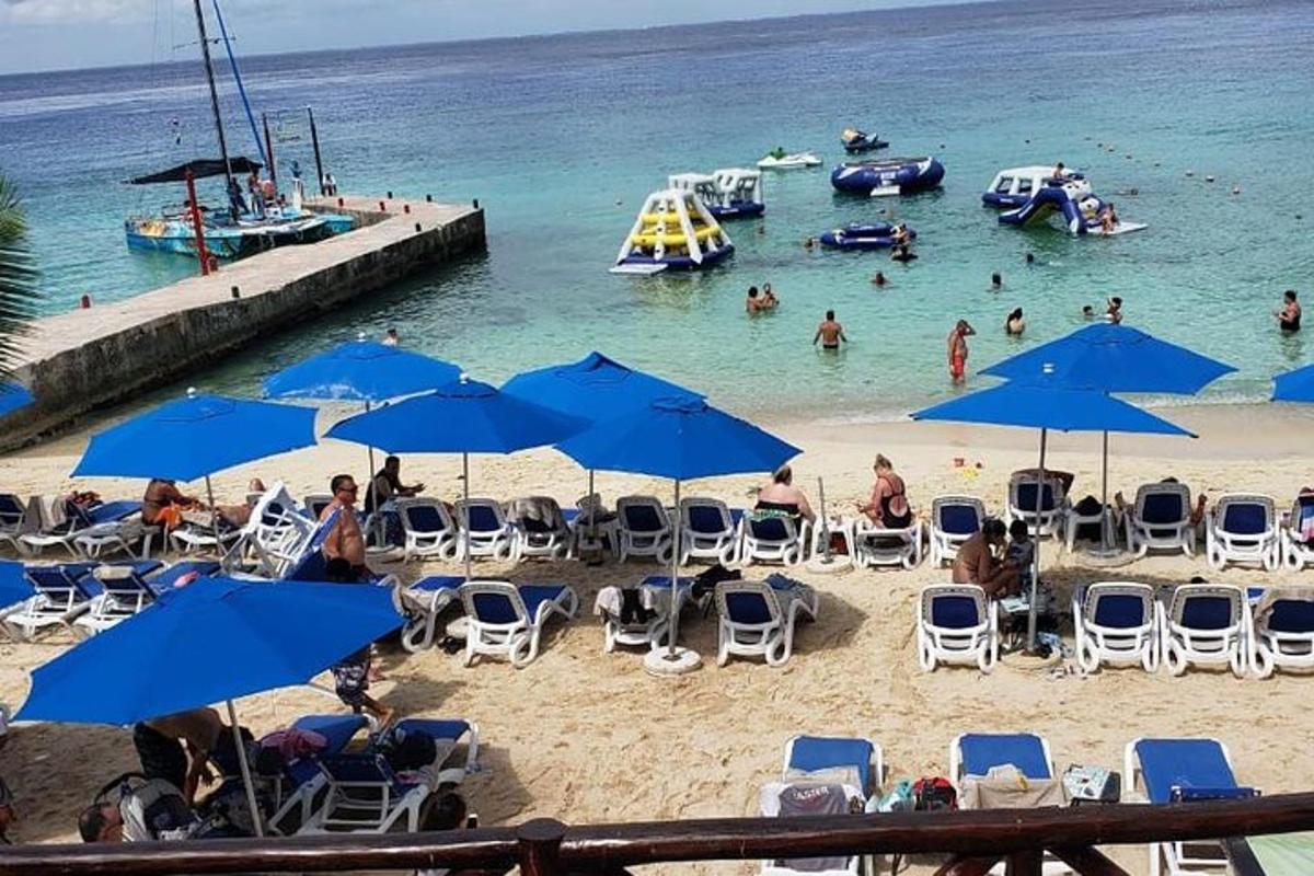 uma praia com guarda-sóis azuis e pessoas na água
