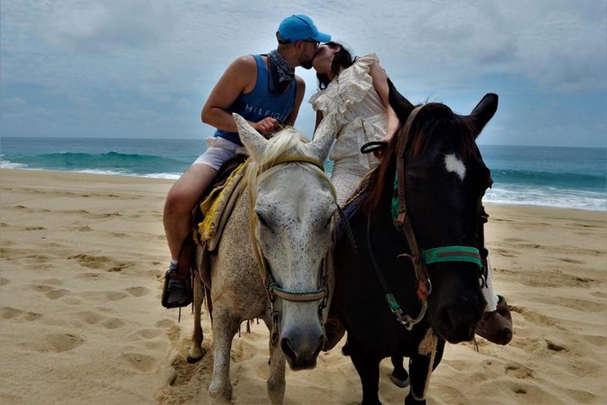 a man and a woman riding a horse on the beach