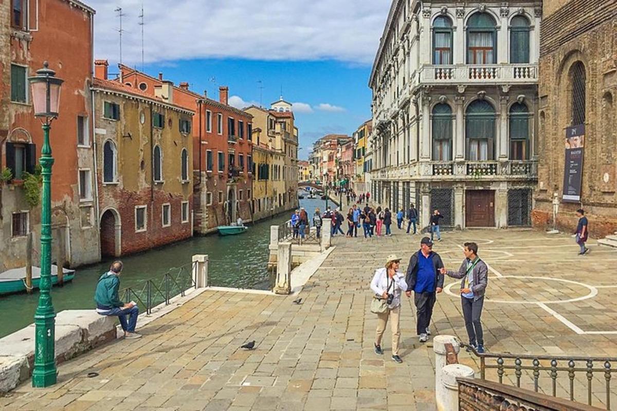Un grupo de personas caminando por una calle junto a un canal.