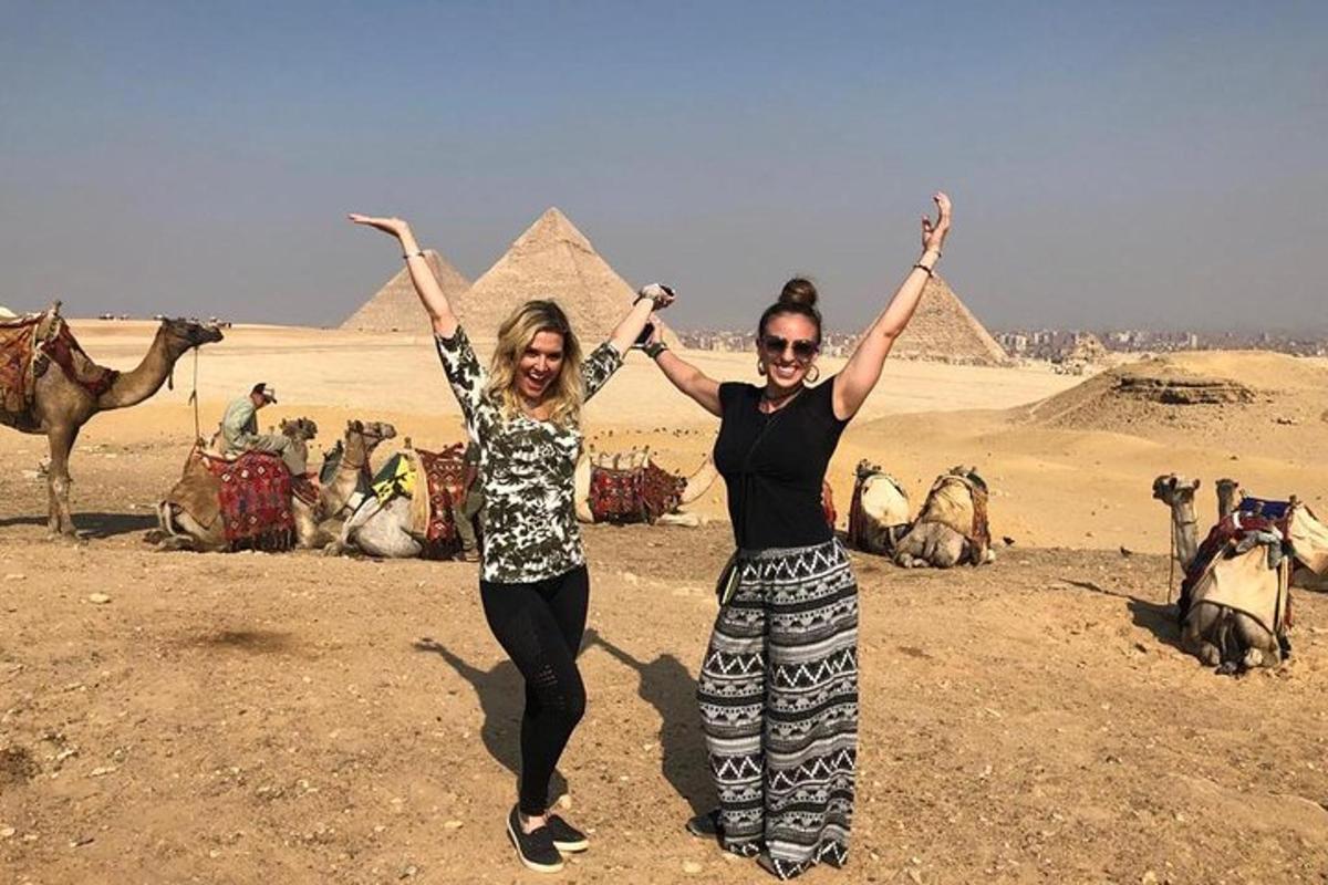 twee vrouwen met hun armen omhoog voor de piramides
