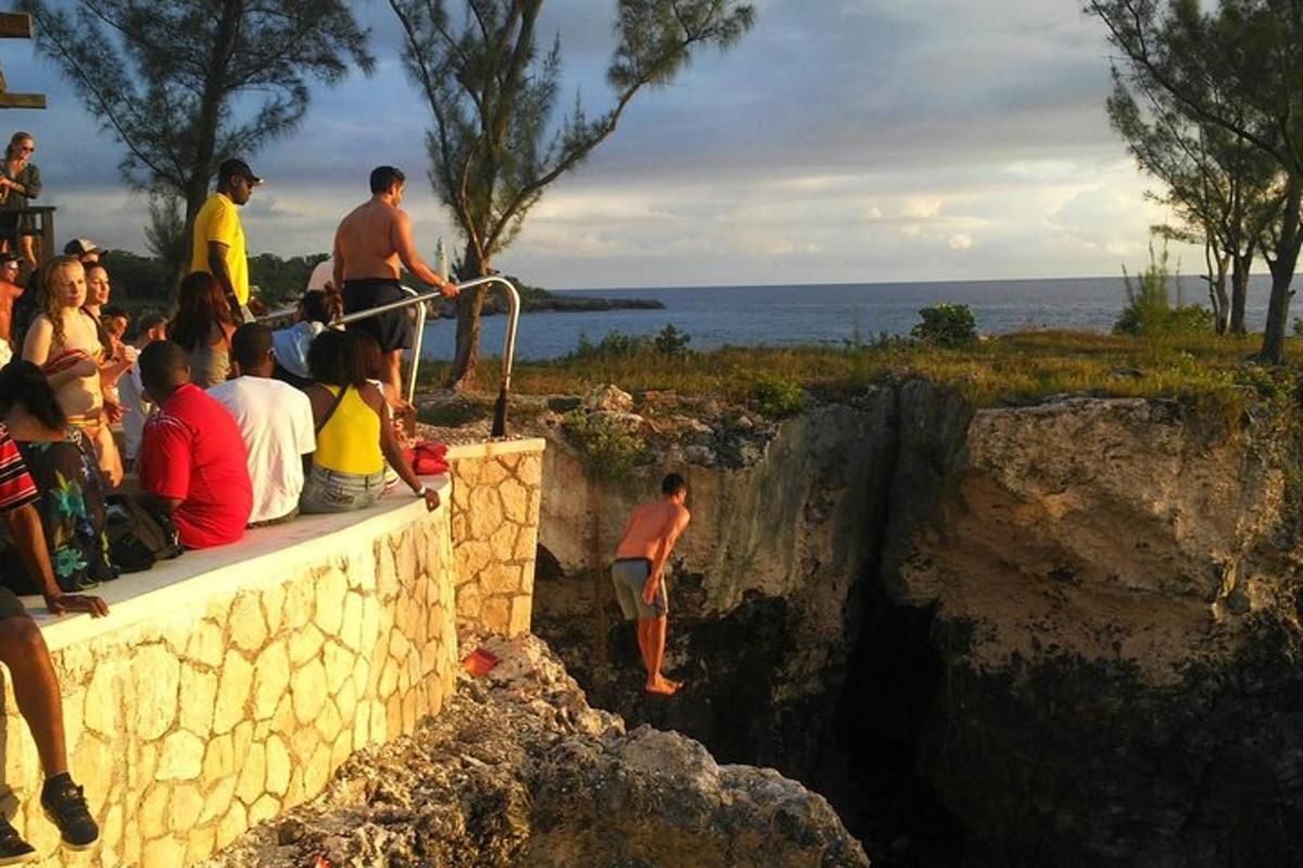 eine Gruppe von Menschen sitzt auf einer Mauer und schaut auf das Wasser