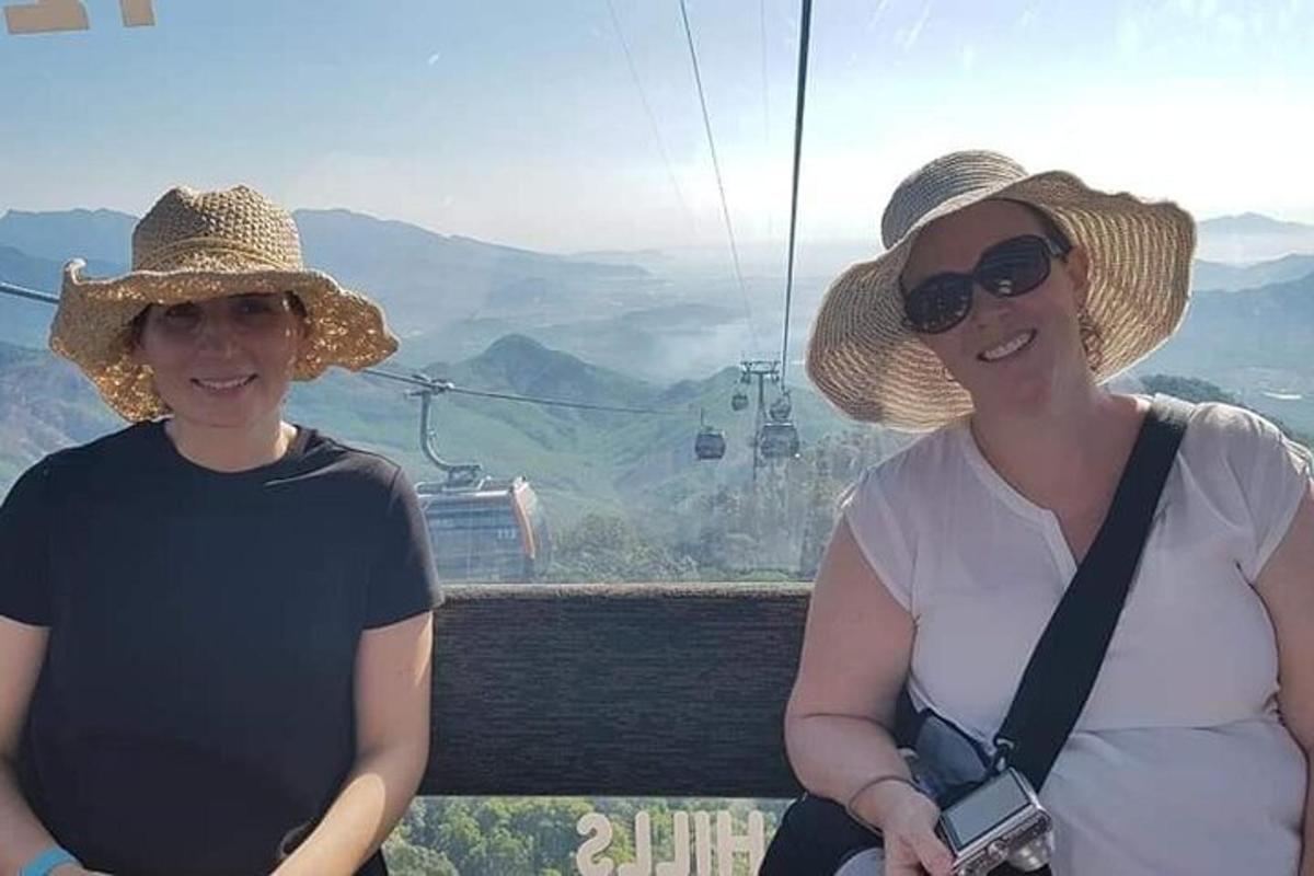 duas mulheres de chapéu em pé em um teleférico