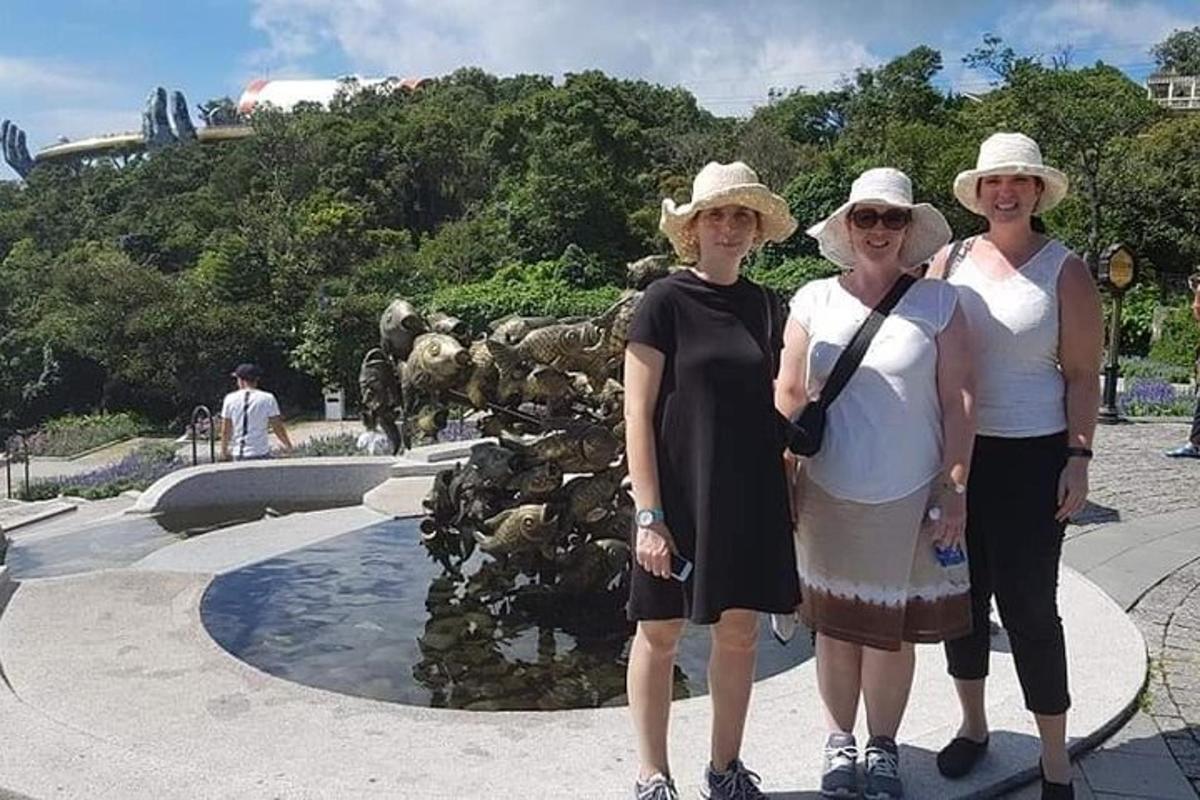 um grupo de três mulheres em pé em frente a uma fonte