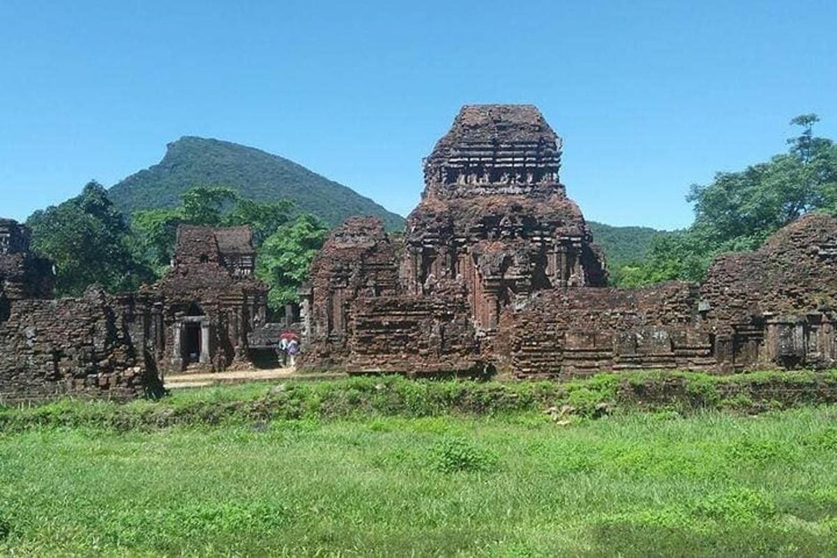 un grande edificio in un campo con una collina sullo sfondo