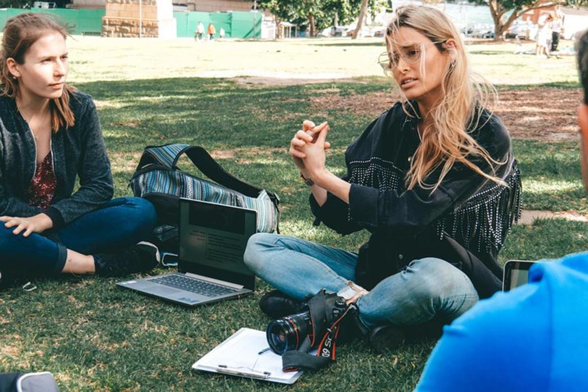 Dos mujeres sentadas en el césped con una computadora portátil