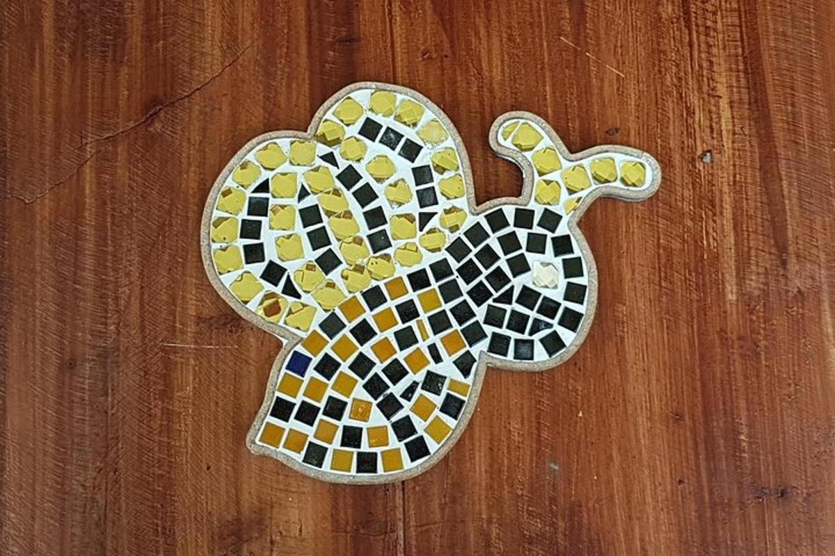 a mosaic tile elephant on a wooden wall