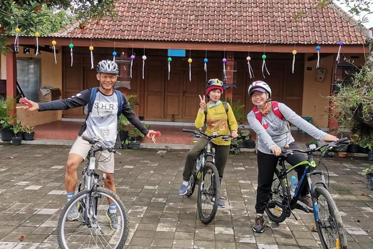 traja ľudia jazdiaci na bicykloch pred domom