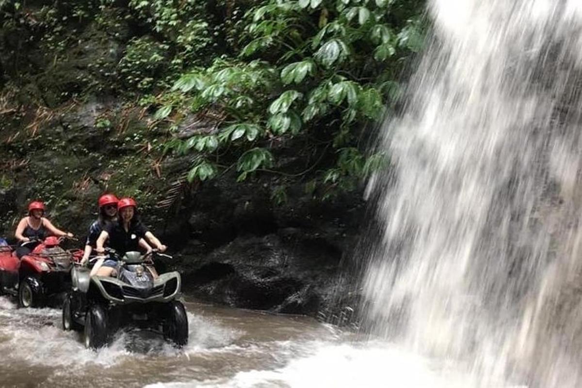 Un grupo de personas viajando en vehículos todo terreno a través de una cascada.
