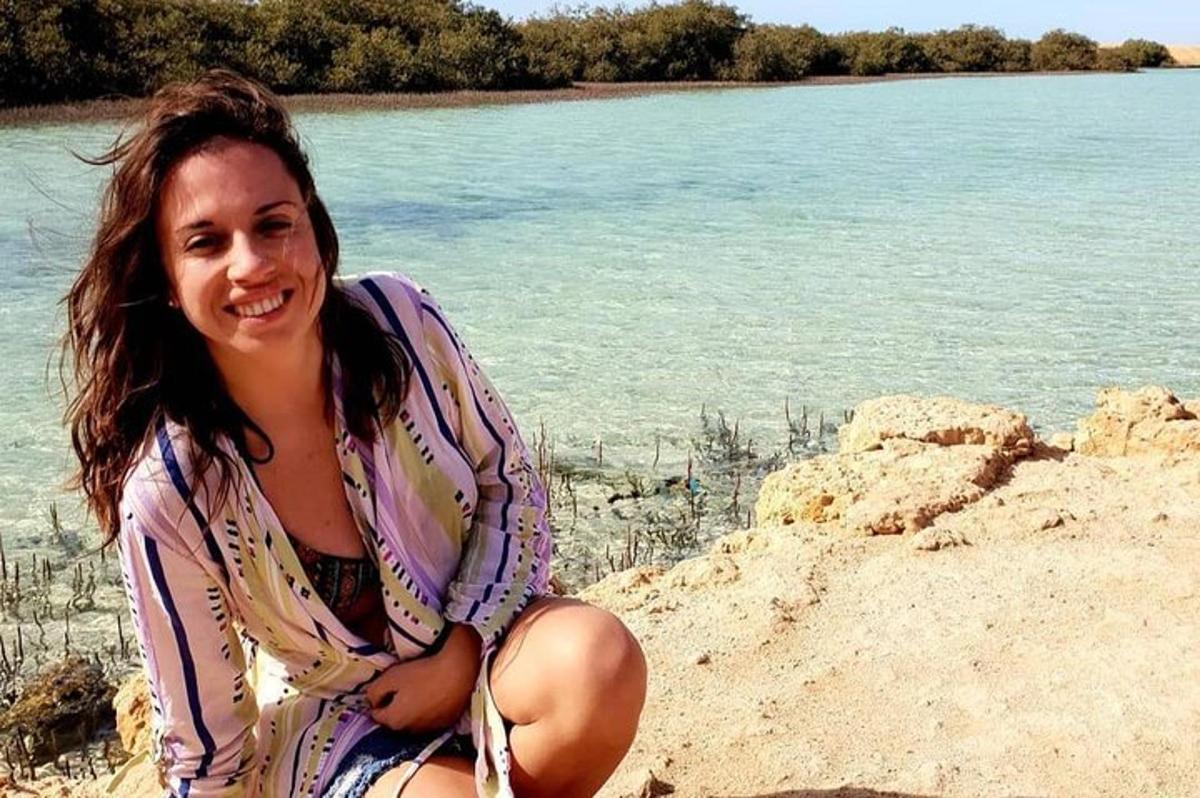 una mujer sentada en la playa junto al agua