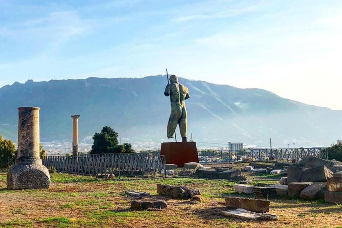 uma estátua de um homem segurando uma lança em um campo