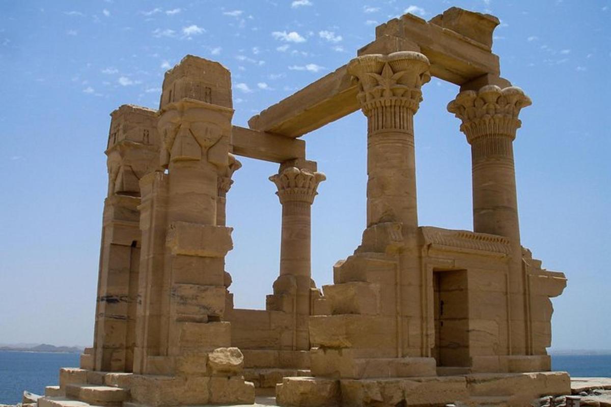 an ancient building with columns in front of the ocean