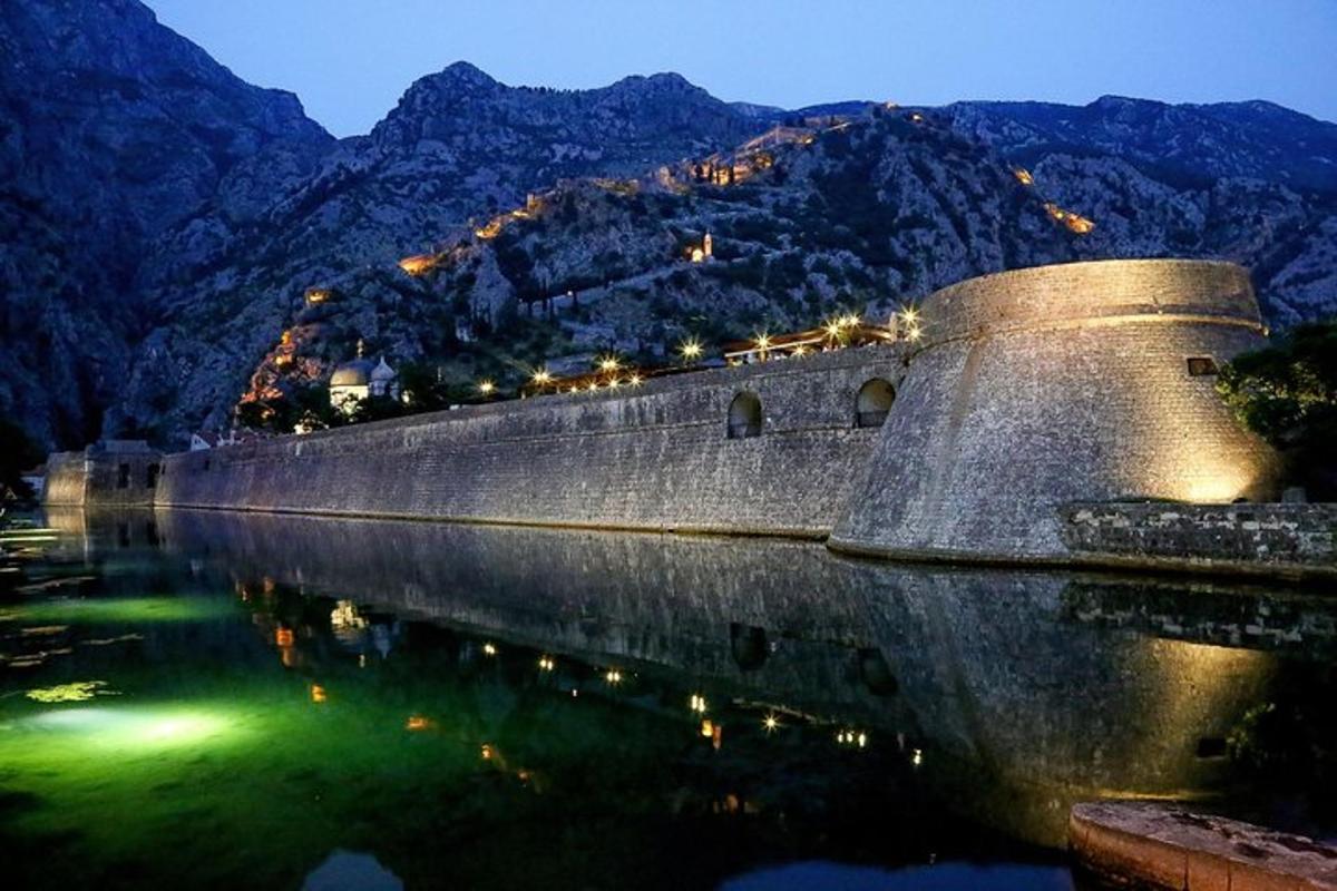 камени зид поред водене површине са планинама