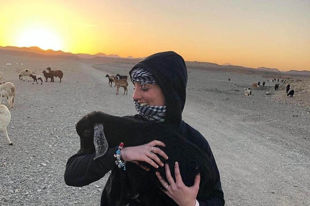 una donna in piedi nel deserto con una mandria di animali