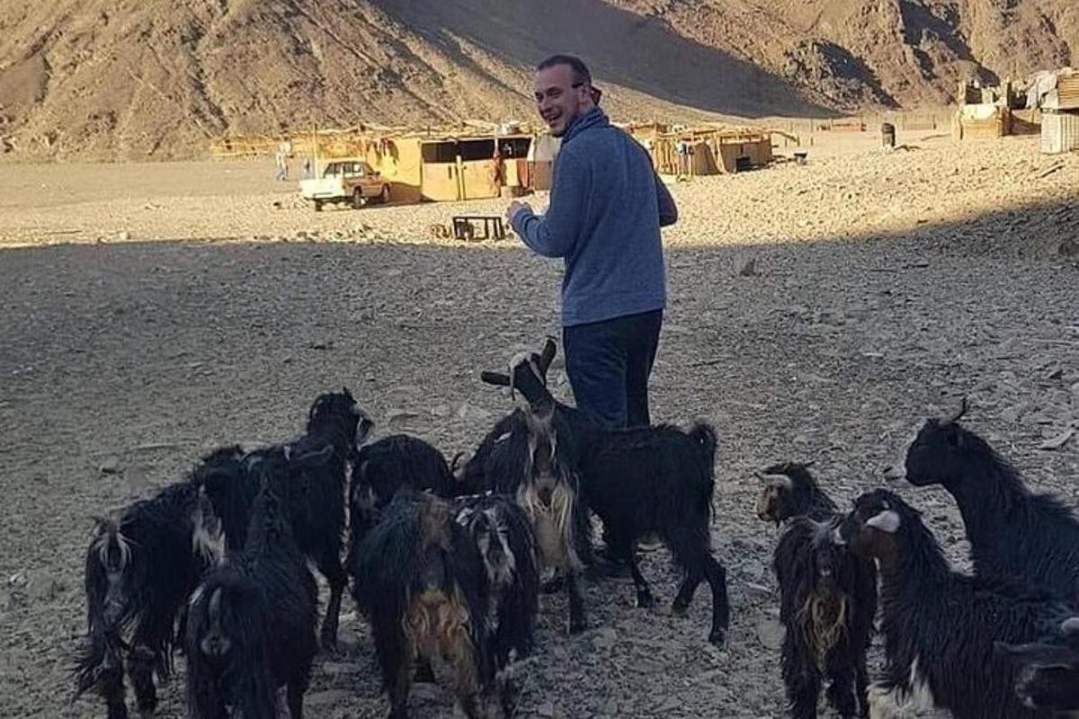 un uomo in piedi davanti a un gregge di capre