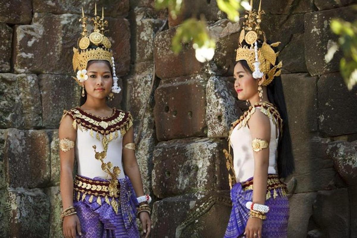 Dos mujeres con trajes tradicionales de pie junto a un muro de piedra