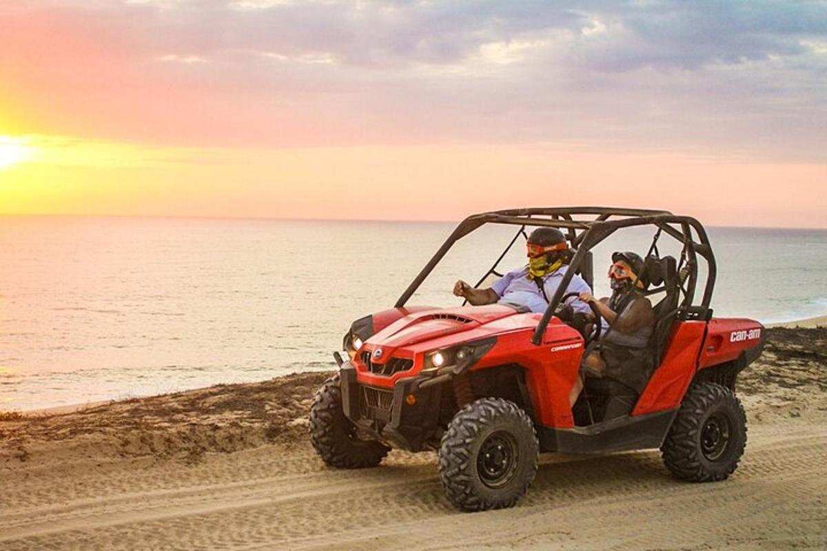 Két ember piros ATV-ben a tengerparton