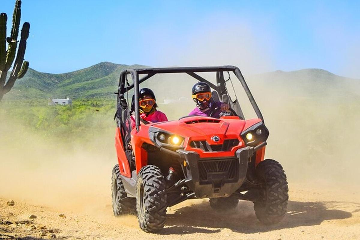 Két ember piros ATV-vel közlekedik egy földúton