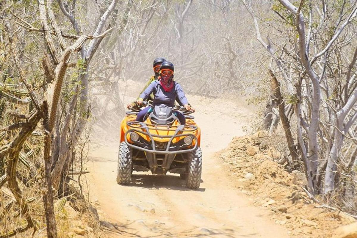 two people riding on a four wheeler on a dirt trail
