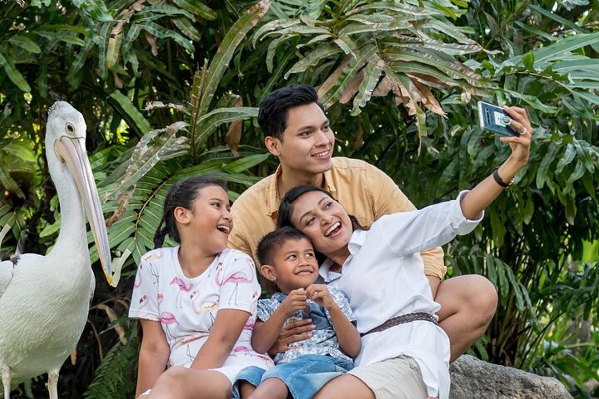 a man taking a picture with two children and a swan