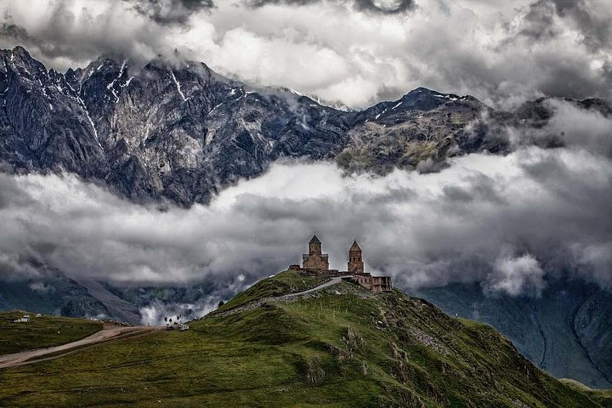 Un castillo en la cima de una colina verde con montañas.