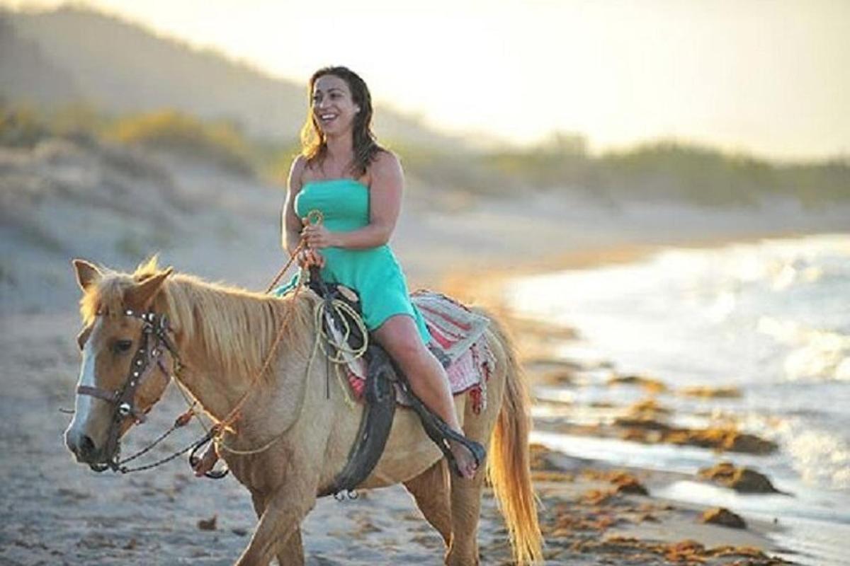 una ragazza con un vestito verde a cavallo sulla spiaggia